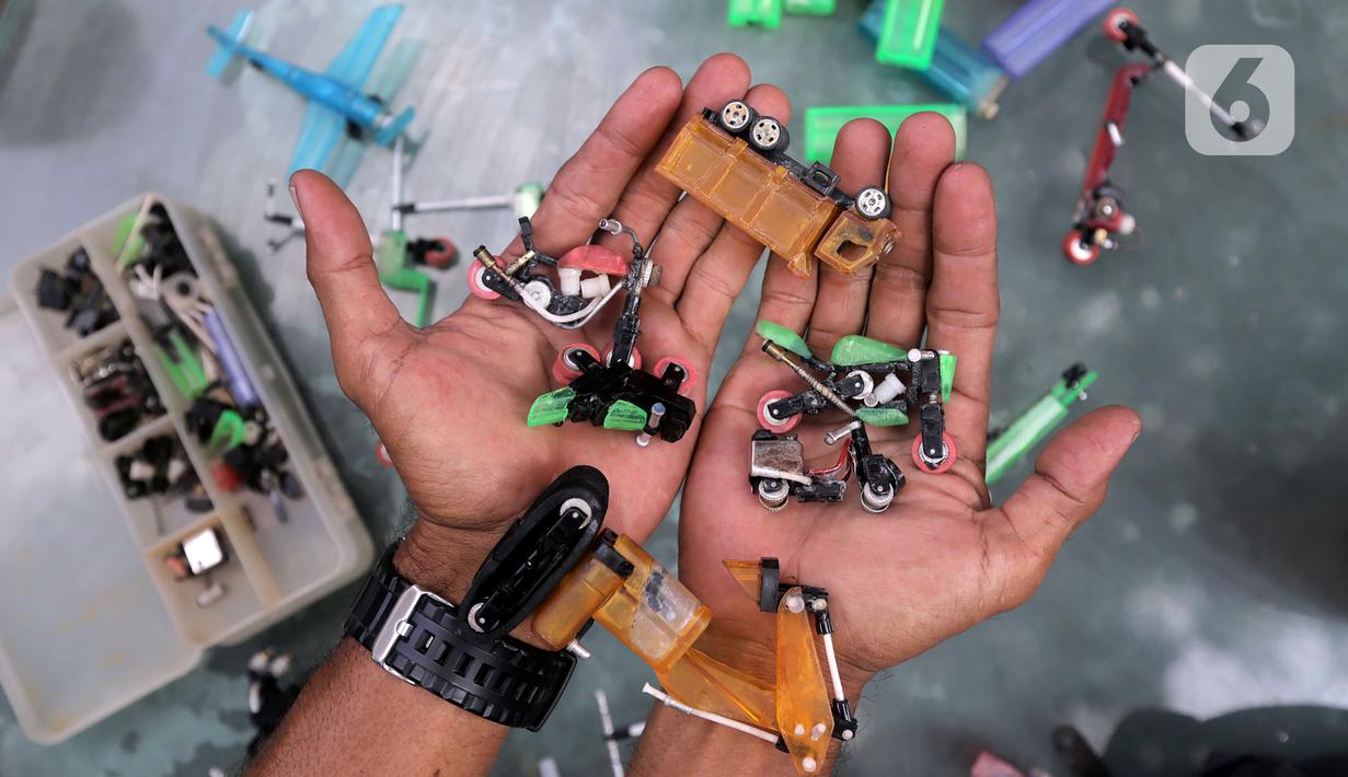 Petugas UPS Badan Air DLH Provinsi DKI Jakarta, Bang Timan menunjukkan miniatur kendaraan yang terbuat dari limbah korek api di Jakarta, Kamis (3/8/2023). Sisi lain Bang Timan adalah beliau dikenal dengan kemampuannya mengubah limbah korek api untuk dijadikan kerajinan tangan yang menarik. (Liputan6.com/Johan Tallo)