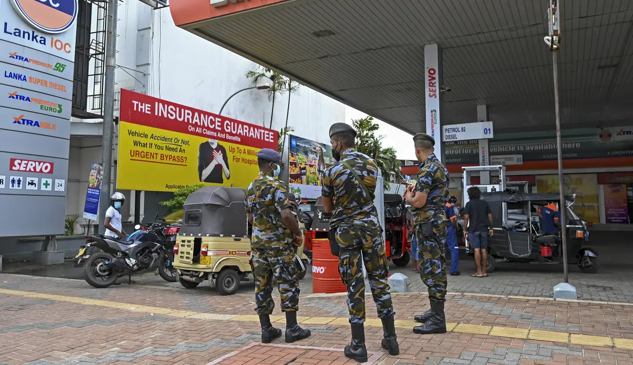 Tentara berjaga saat pengendara antre untuk membeli bahan bakar di stasiun bahan bakar Lanka IOC di Kolombo, Selasa (24/5/2022). Sri Lanka yang kekurangan uang menaikkan harga bahan bakar secara tajam ke rekor tertinggi pada 24 Mei 2022, menyebabkan penderitaan lebih lanjut bagi 22 juta orang di negara itu dalam krisis terburuk sejak kemerdekaan. (Ishara S. KODIKARA / AFP)