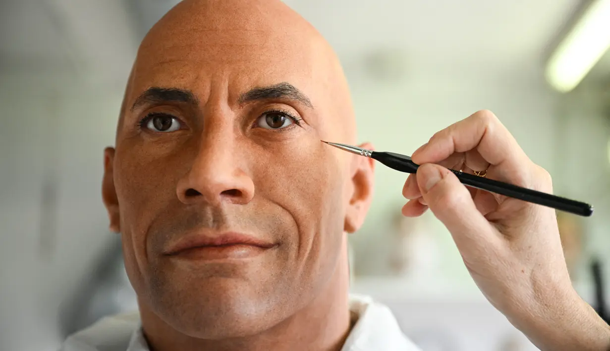 Pihak Museum Grevin di Paris tengah memperbaiki patung lilin aktor Dwayne Johnson atau yang biasa dikenal dengan The Rock. (Stefano RELLANDINI / AFP)