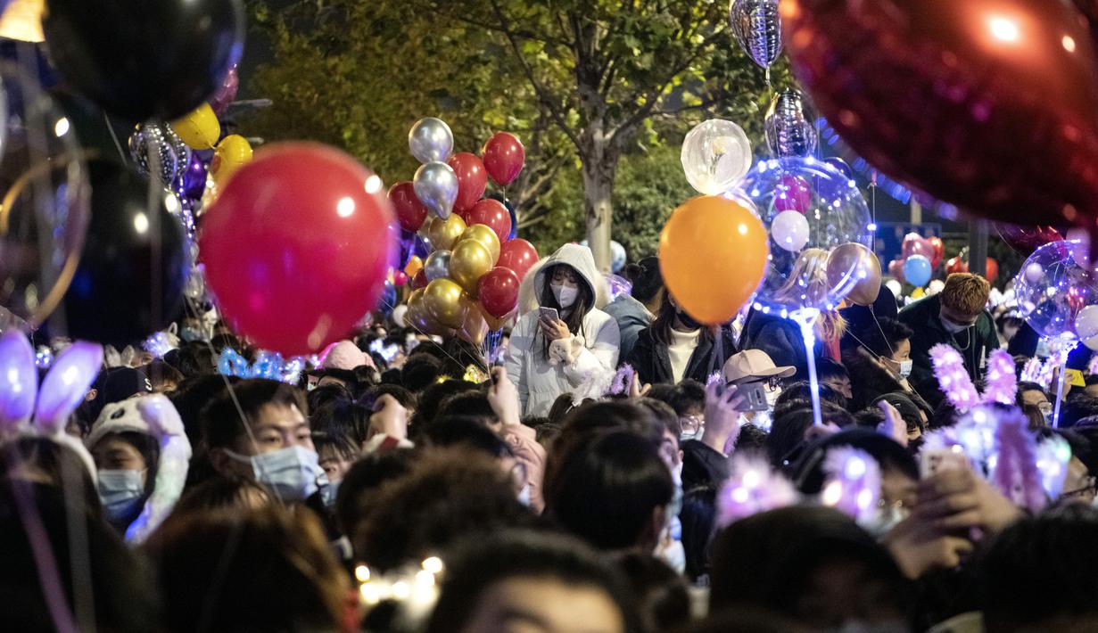 Orang-orang menghadiri  hitung mundur di Wuhan, provinsi Hubei, China (1/1/2021). Banyak yang membawa balon untuk dilepaskan ketika jam menunjukkan pukul 12 pagi. (AFP/Noel Celis)
