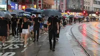 Pengunjuk rasa membawa payung saat menuju Victoria Park, Hong Kong, Minggu (18/8/2019). Puluhan ribu massa pro-demokrasi membawa payung saat hujan mengguyur Victoria Park dan sekitarnya. (AP Photo/Kin Cheung)