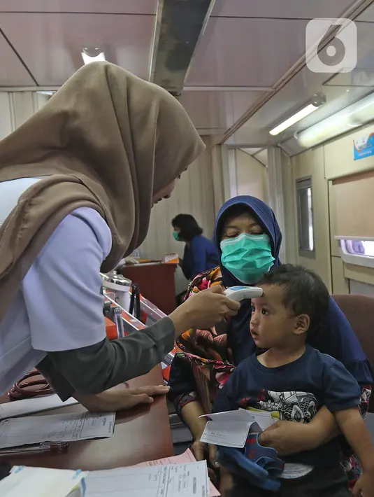Petugas medis mengecek suhu tubuh seorang anak melalui Rail Clinic di stasiun kereta Depok, Jumat (6/3/2020).  PT KAI Daop 1 melakukan kegiatan  sosialisasi mengenai penyebaran virus corona dengan menghadirkan kereta kesehatan Rail Clinic. (Liputan6.com/Herman Zakharia)