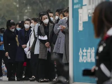 Wanita yang memakai masker wajah mengantre untuk mendapatkan tes usap tenggorokan COVID-19 rutin mereka di tempat pengujian virus corona di Beijing, Rabu (26/10/2022). Kota Shanghai di China mulai memberikan vaksin COVID-19 yang dapat dihirup pada hari Rabu di tempat yang tampaknya menjadi yang pertama di dunia. (AP/Andy Wong)