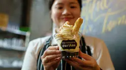 Seorang anggota staf restoran menunjukkan secangkir es krim rasa durian di kafe Mao Shan Wang di Singapura (24/1). (AFP Photo/Nicholas Yeo)