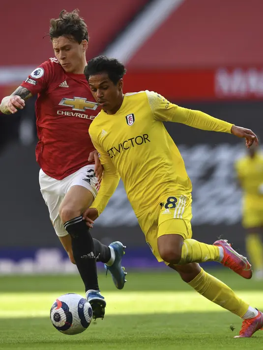 Gelandang Fulham, Fabio Carvalho berebut bola dengan bek Manchester United (MU), Victor Lindelof pada pekan 37 Liga Inggris di Stadion Old Trafford, Rabu (19/5/2021) dinihari WIB. MU kembali gagal menang setelah ditahan imbang 1-1 oleh tamunya Fulham. ((AP Photo/Paul Ellis, Pool)