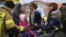 Petugas damkar Polandia membantu pengungsi Ukraina membawa barang-barang di perbatasan Medyka, Rabu (30/3/2022). Badan pengungsi PBB mengatakan kini lebih dari 4 juta orang telah meninggalkan Ukraina, tonggak baru dalam krisis pengungsi terbesar di Eropa sejak Dunia Perang II. (AP/Sergei Grits)