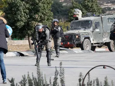 Pasukan keamanan Israel bersiap menembak pria Palestina setelah dia menikam seorang tentara di kota al-Bireh, Tepi Barat yang diduduki Israel (15/12). Pria tersebut membawa pisau dan diduga memegangi benda diduga bom. (AFP Photo/Oren Ziv)