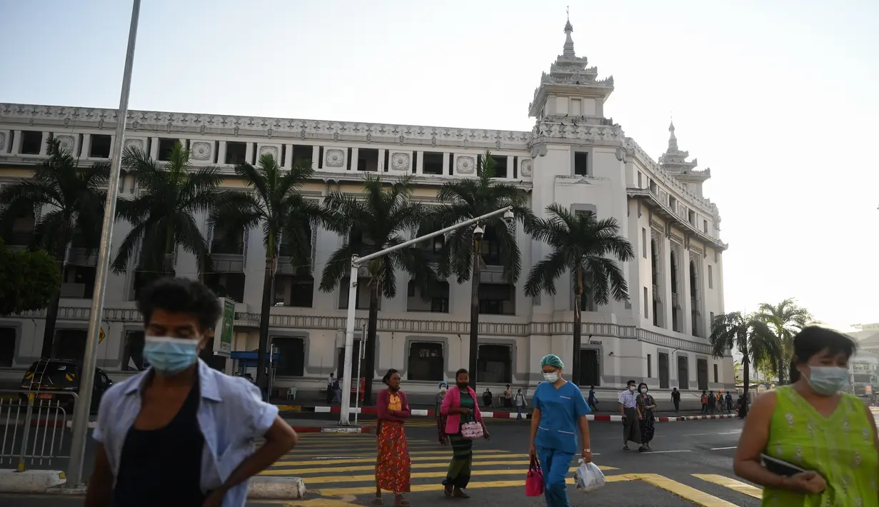 Orang-orang berjalan di sebelah Balai Kota Yangon di Yangon ketika militer menahan pemimpin de facto Myanmar Aung San Suu Kyi dan presiden Myint dalam kudeta, pada Senin (1/2/2021). Langkah itu terjadi beberapa hari setelah meningkatnya ketegangan antara pemerintah sipil dan militer yang berkuasa.