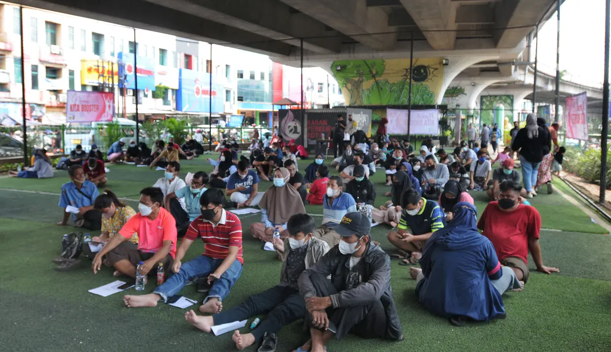Warga dan pedagang pasar antre menunggu giliran untuk vaksinasi dosis ke-3 di kolong flyover Ciputat, Tangerang Selatan, Sabtu (2/4/2022). Vaksinasi booster tersebut diselenggarakan oleh Polsek Ciputat Timur dan Polres Tangerang Selatan. (merdeka.com/Arie Basuki)