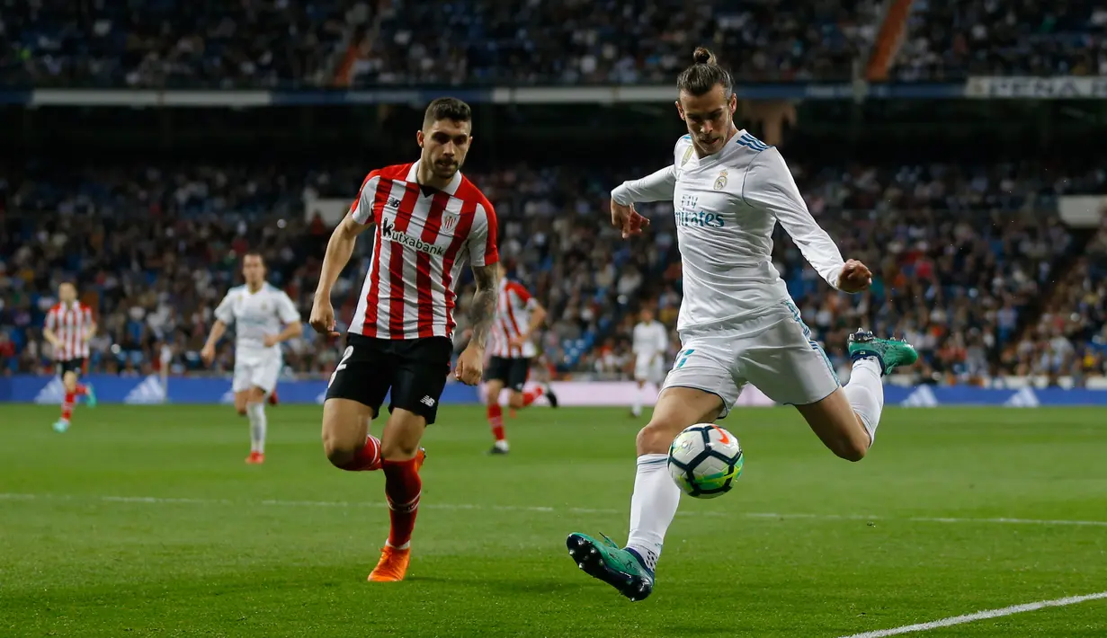 Pemain Real Madrid, Gareth Bale berebut bola dengan pemain Athletic Bilbao, Unai Nunez pada pekan ke-33 La Liga di Santiago Bernabeu, Rabu (18/4). Real Madrid kembali meraih hasil minor usai bermain imbang 1-1 lawan Atletico Bilbao. (AP/Francisco Seco)