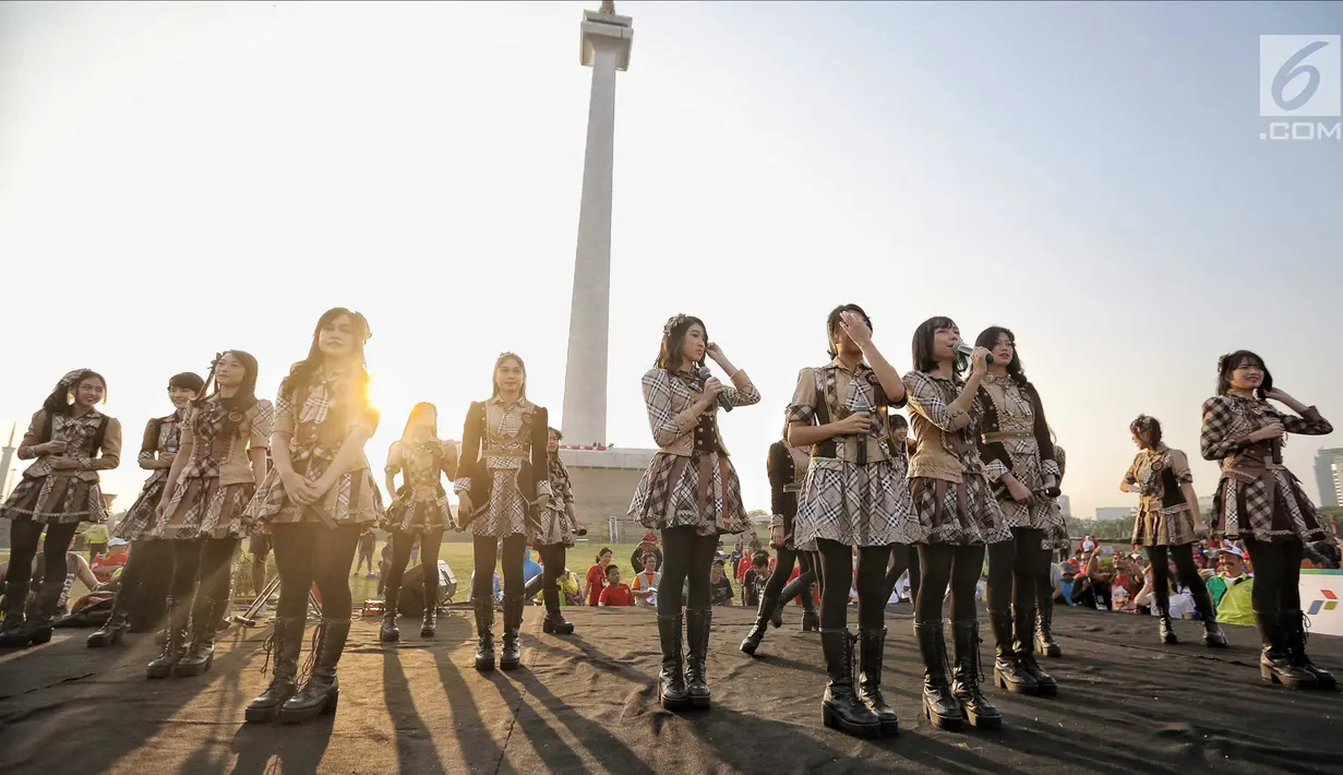 Aksi para personel girlband JKT48 saat tampil dalam puncak Kirab Obor Asian Games 2018 di Monas, Jakarta, Sabtu (18/8). Obor Asian Games 2018 diarak dari Monumen Nasional (Monas) menuju Stadion Utama Gelora Bung Karno (SUGBK). (Liputan6.com/Faizal Fanani)