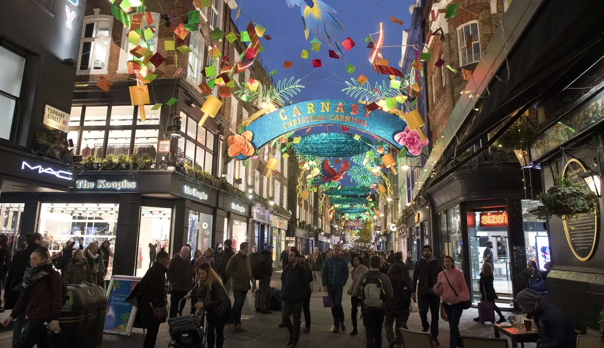 Pengunjung berjalan di bawah lampu perayaan Natal di Carnaby Street, di pusat kota London, Inggris (5/12). (AFP Photo/Justin Tallis)