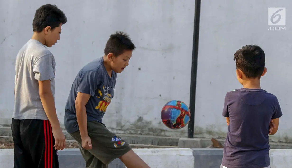 Anak-anak pencari suaka bermain sepak bola di halaman bekas Markas Kodim di Kalideres, Jakarta, Selasa (16/7/2019). Sebelumnya, para pencari suaka dari berbagai negara berkonfilk ini tinggal di pinggir jalan dan trotoar di kawasan Kebon Sirih, Jakarta. (Liputan6.com/Helmi Fithriansyah)