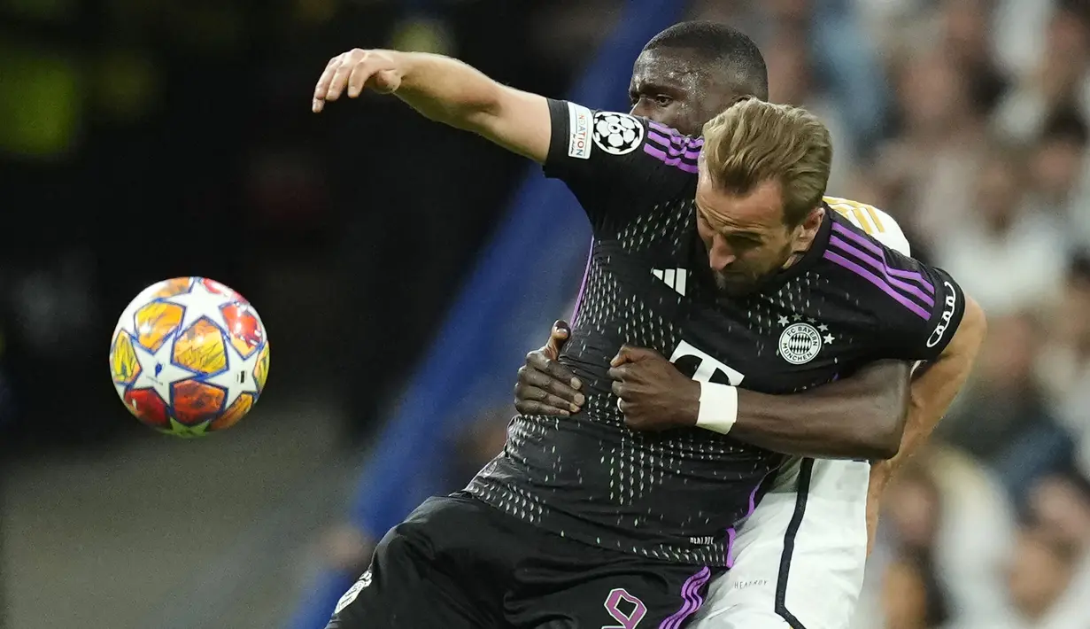 Striker Bayern Munchen, Harry Kane (kiri) menguasai bola dibayangi bek Real Madrid, Antonio Rudiger pada laga leg kedua semifinal Liga Champions 2023/2024 di Santiago Bernabeu Stadium, Madrid, Rabu (8/5/2024). (AP Photo/Jose Breton)