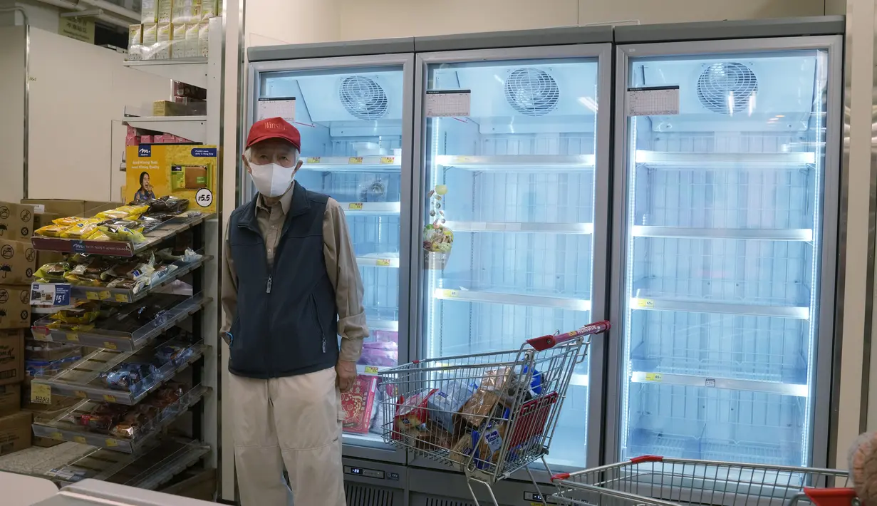 Seorang pria berdiri di deretan lemari es kosong saat warga yang panik menimbun makanan di supermarket Hong Kong, Jumat (4/3/2022). Pemimpin Hong Kong awal pekan ini mengatakan mobilitas orang mungkin dibatasi selama tes covid-19 massal wajib ketika kasus harian mencapai rekor. (AP Photo/Kin Cheung)