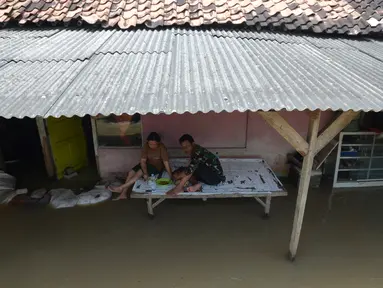 Aktivitas warga terdampak banjir di Desa Sindangsari, Kabupaten Bekasi, Jawa Barat, Rabu (24/2/2021). Sebagian rumah warga masih terendam banjir yang disebabkan jebolnya tanggul Sungai Citarum dan luapan Sungai Ciherang. (merdeka.com/Imam Buhori)