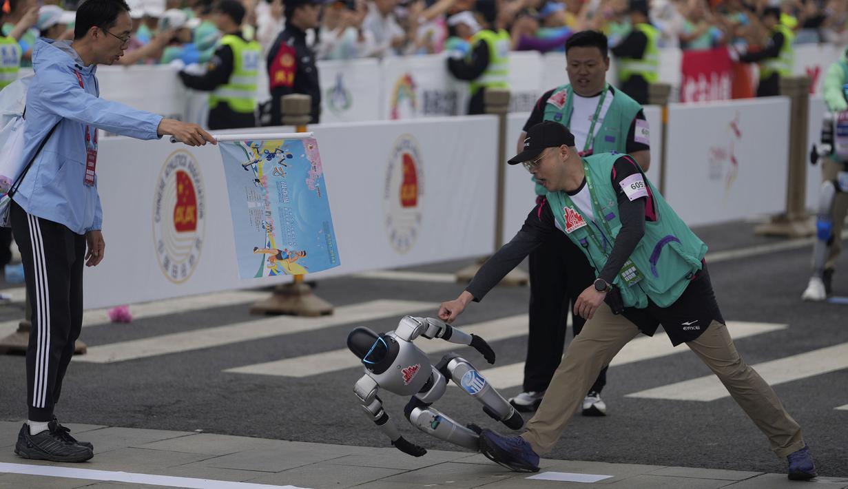 Sebuah robot humanoid kehilangan keseimbangan saat melewati garis finis dalam ajang lari half marathon yang berlangsung di Beijing, China, Sabtu (19/04/2025). (AP Photo/Ng Han Guan)