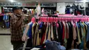Pengunjung mencoba pakaian bekas impor yang dijajakan pedagang di Pasar Baru Metro Atom, Jakarta, Jumat (6/12/2019). Pakaian bekas impor yang dijual di kios-kios pasar masih banyak diminati lantaran harga yang ditawarkan sangat terjangkau. (merdeka.com/Imam Buhori)