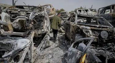 Seorang pria Palestina berjalan di antara mobil-mobil yang hangus di tempat pembuangan sampah, di kota Hawara, dekat kota Nablus di Tepi Barat, Senin, 27 Februari 2023. Puluhan pemukim Israel mengamuk dengan kekerasan di Tepi Barat utara, membakar  mobil dan rumah-rumah setelah dua pemukim dibunuh oleh seorang pria bersenjata Palestina. (AP Photo/Ohad Zwigenberg)