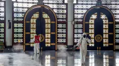 Pekerja dari otoritas penanggulangan bencana setempat menyemprotkan desinfektan di sebuah masjid di Surabaya, Jawa Timur, Selasa (17/3/2020). Kegiatan tersebut dilakukan untuk mencegah penyebaran Virus Corona COVID-19. (Photo by Juni Kriswanto / AFP)