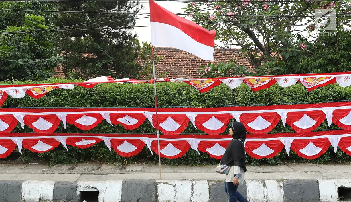 Warga melintas di depan bendera dan aksesori kemerdekaan RI, Jakarta Selatan, Selasa (1/8). Penjualan bendera serta aksesori kemerdekaan ditawarkan dengan harga bervariasi, mulai Rp10ribu hingga Rp250ribu. (Liputan6.com/Immanuel Antonius)