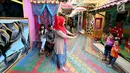 Seorang ibu memfoto anaknya di depan mural di Kampung Warna-warni Jodipan dan Kampung Tridi (3D) di pinggir Sungai Brantas, Tumenggungan Ledok, Blimbing, Kota Malang, Jawa Timur (29/7). (Liputan6.com/Johan Tallo)