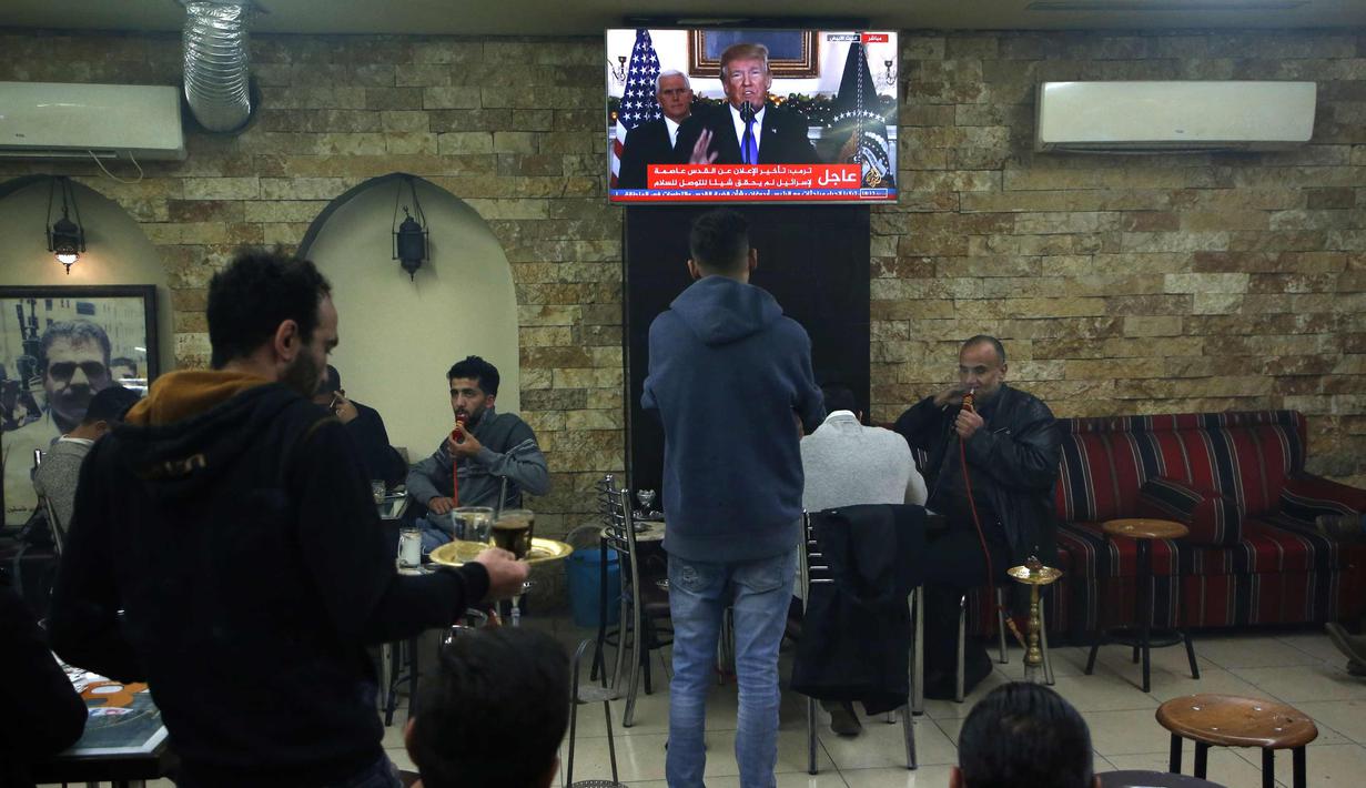 Seorang warga Palestina menyaksikan pidato Presiden AS, Donald Trump dari televisi saat mengumumkan bahwa AS mengakui Yerusalem sebagai ibu kota Israel di sebuah kafe di kota Ramallah (6/12). (AFP Photo/Abbas Momani)