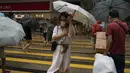 Orang-orang memegang payung di bawah angin kencang berjalan melewati penyeberangan saat badai tropis Ma-on melewati Hong Kong, Kamis (25/8/2022). Badai Tropis Ma-on semakin kuat saat menuju Hong Kong dan bagian tenggara lainnya China pada hari Rabu setelah menggusur ribuan orang di Filipina. (AP Photo/Anthony Kwan)