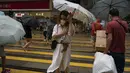 Orang-orang memegang payung di bawah angin kencang berjalan melewati penyeberangan saat badai tropis Ma-on melewati Hong Kong, Kamis (25/8/2022). Badai Tropis Ma-on semakin kuat saat menuju Hong Kong dan bagian tenggara lainnya China pada hari Rabu setelah menggusur ribuan orang di Filipina. (AP Photo/Anthony Kwan)