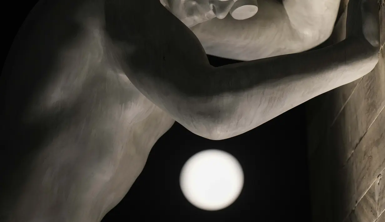Bulan purnama muncul di atas patung 'Mr Arbitrium' karya seniman Italia Emanuele Giannelli bersandar ke Peace Arch, di Milan, Italia, Rabu (13/7/2022). Bulan Purnama dikenal sebagai Buck Moon dan juga Supermoon. Fenomena tersebut hanya terjadi setiap 9 tahun sekali, dan terakhir kali muncul pada 2013 lalu. (AP Photo/Luca Bruno)