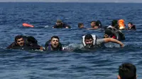 Sejumlah pengungsi Suriah menggunakan pelampung dan berenang menuju pantai setelah perahu yang ditumpangi bocor sekitar 100 m sebelum mencapai pulau Lesbon, Yunani, Minggu (13/09/2015). (REUTERS/Alkis Konstantinidis)