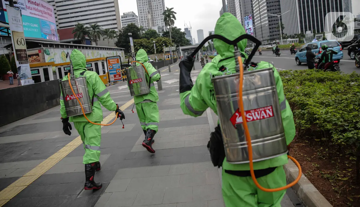Petugas menyemprotkan cairan disinfektan di ruang publik kawasan pedestrian Sudirman, Jakarta, Kamis (19/3/2020). Penyemprotan dilakukan untuk antisipasi dan pencegahan penyebaran COVID-19 di lingkungan ruang publik yang banyak di gunakan oleh masyarakat. (Liputan6.com/Faizal Fanani)