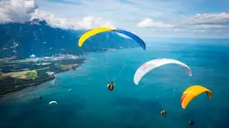 Pemandangan Danau Jenewa yang dihiasi warna-warni dari paraglider yang melakukan penerbangan di Villeneuve, Swiss (20/8). Olahraga paragliding lepas landas dari sebuah lereng bukit atau gunung dengan memanfaatkan angin. (Valentin Flauraud Keystone via AP)