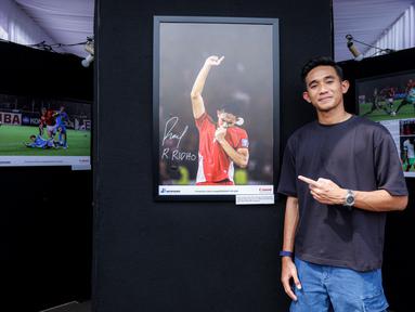 Pemain Timnas Indonesia, Rizky Ridho berfoto bersama dengan karya foto milik Ady Sesotya yang memperlihatkan dirinya tengah berselebrasi mencium logo garuda di jerseynya setelah Skuad Garuda menang 1-0 atas Bahrain di Kualifikasi Piala Dunia 2026 saat pameran foto Media Cup 2025 bertema "Timnas Indonesia dari Masa ke Masa" di Cibis, Cilandak, Jakarta Selatan, Selasa (28/10/2025). (Bola.com/Bagaskara Lazuardi)
