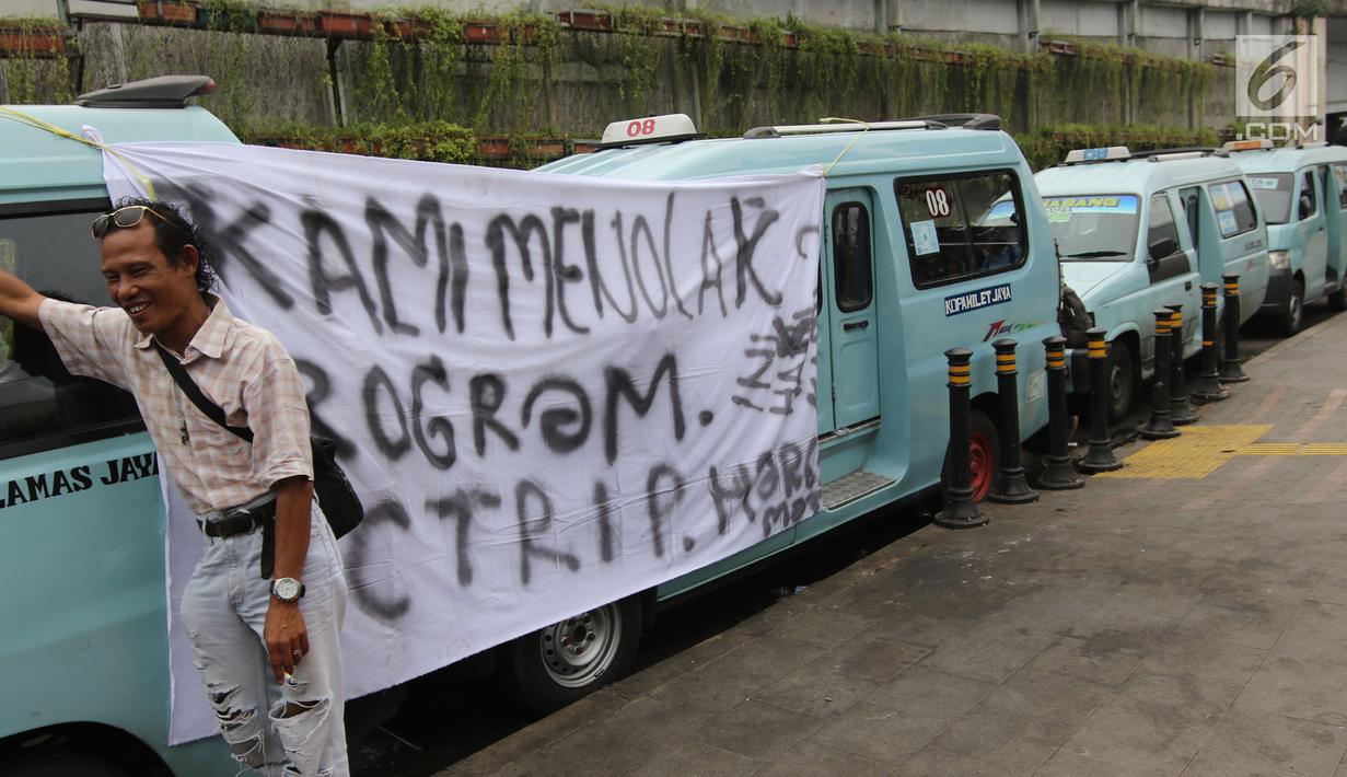 Sopir angkot M08 trayek Tanah Abang-Kota membentangkan spanduk berisi penolakan di Jalan Jatibaru, Jakarta, Kamis (22/2). Para sopir angkot menggelar aksi mogok beroperasi untuk menolak sejumlah syarat dari program OK Otrip. (Liputan6.com/Arya Manggala)
