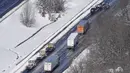 Kendaraan derek menuju ke mobil dan truk yang terdampar di bagian Interstate 95 di Ladysmith, Virginia, Selasa (4/1/2022). Hampir 48 mil dari Interstate ditutup karena es dan salju. (AP Photo/Steve Helber)