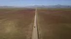 Sebuah mobil melaju di jalan di gurun Atacama yang dipenuhi bunga-bunga bermekaran, dekat Copiapo, Chili, Selasa, 4 Oktober 2022. Fenomena ini biasanya hanya terjadi setiap lima hingga tujuh tahun ketika hujan lebat yang jarang menyebabkan bunga bermekaran. (AP Photo/Matias Basualdo)