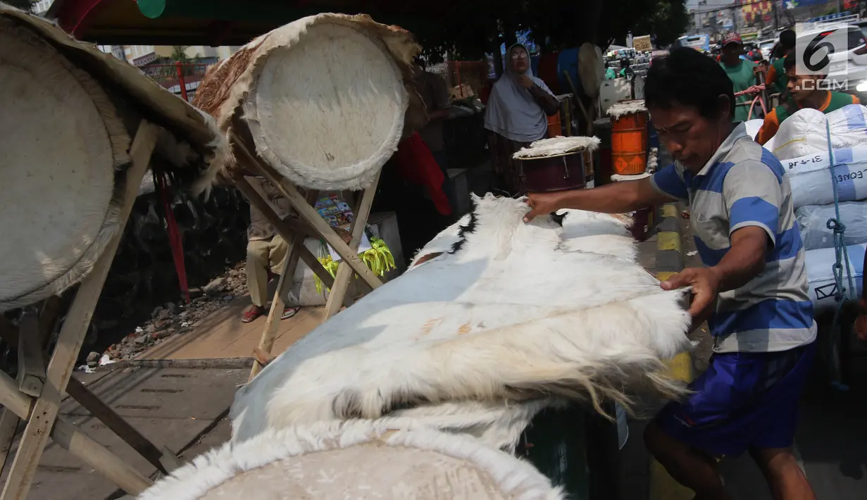 Seorang penjual membuat bedug untuk di jual di Jalan KH Mas Mansyur, Tanah Abang, Jakarta, Kamis (31/5). Bedug tersebut dijual dengan kisaran harga Rp 150 ribu hingga Rp 3 juta rupiah. (Liputan6.com/Arya Manggala)