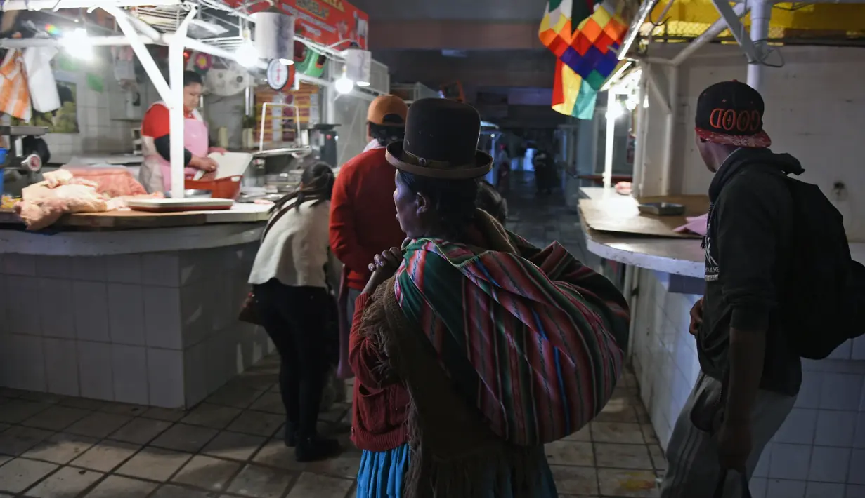 Orang-orang berjalan untuk membeli daging di Pasar Rodriguez, La Paz, pada 16 November 2019. Pemblokiran jalan yang dilakukan pendukung mantan Presiden Bolivia Evo Morales membuat kelangkaan bahan makanan, terutama daging dan telur, mulai sulit ditemukan di pasar. (AIZAR RALDES/AFP)
