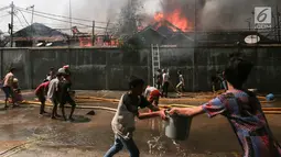 Warga mencoba memadamkan api yang membakar pemukiman padat penduduk di kawasan Manggarai, Jakarta, Rabu (10/7/2019). Tidak ada laporan korban dalam kebakaran ini, sementara kerugian yang diderita masih dalam penanganan petugas di lokasi. (Kapanlagi.com/Budy Santoso)