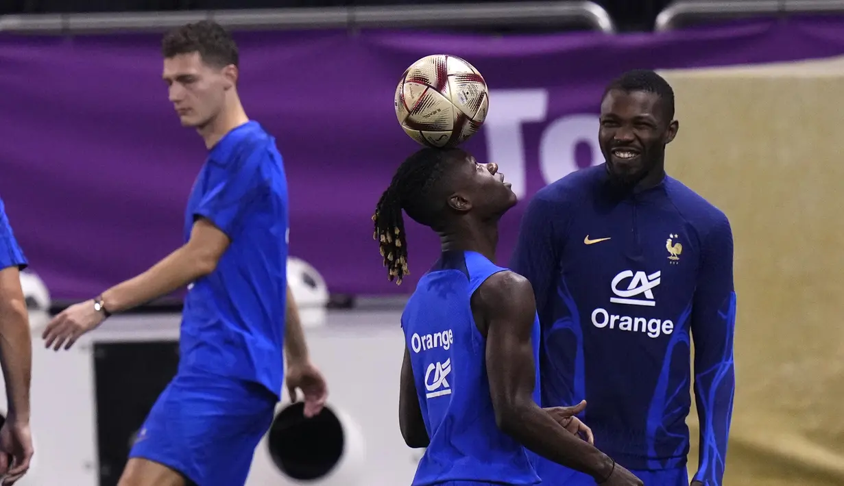 Gelandang Prancis, Eduardo Camavinga mengontrol bola saat rekannya melihat tersenyum saat sesi latihan di stadion Jassim Bin Hamad di Doha, Qatar, Jumat (16/12/2022). Prancis akan melawan Argentina pada pertandingan final Piala Dunia 2022 di Lusail Iconic Stadium, Minggu (18/12/2022). (AP Photo/Petr David Josek)