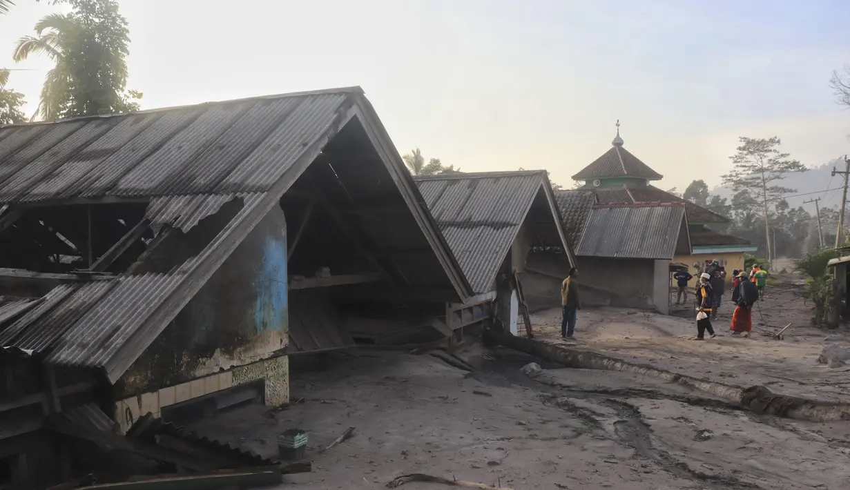 Penduduk desa memeriksa kerusakan saat rumah terlihat terkubur abu vulkanik dari letusan Gunung Semeru di desa Kajar Kuning di Lumajang, Jawa Timur, Indonesia, Senin, 5 Desember 2022. Petugas Pos Pengamatan Gunung Api (PPGA) Semeru, Mukdas Sofian mengatakan, aktivitas Gunung Semeru pada periode pengamatan 5 Desember 2022 pukul 00.00-06.00 WIB mengalami satu kali awan panas guguran dengan amplitudo 25 mm dan lama gempa 386 detik. (AP Photo/Imanuel Yoga)