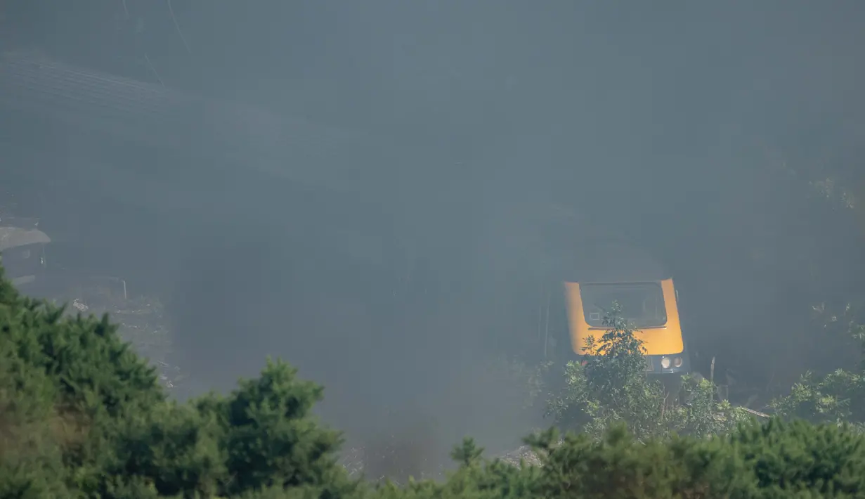 Asap mengepul di atas gerbong yang tergelincir di tempat kecelakaan kereta api dekat Stonehaven di timur laut Skotlandia (12/8/2020). (AFP/MICHAL WACHUCIK)