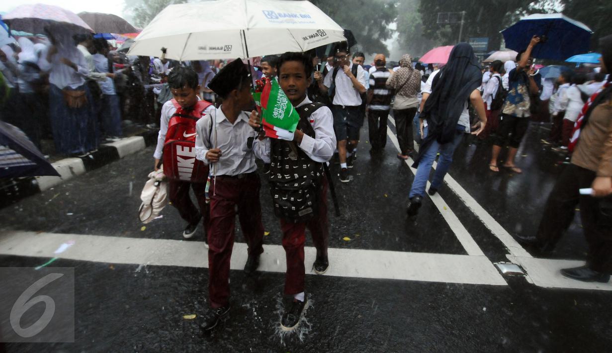 Sejumlah pelajar SD membawa bendera kedua negara usai menyambut kedatangan Raja Salman di sekitar Istana Bogor, Rabu (1/3). Kedatangan Raja Salman bin Abdulaziz ke Istana Bogor disambut puluhan ribu pelajar dan warga. (Liputan6.com/Helmi Fithriansyah) 