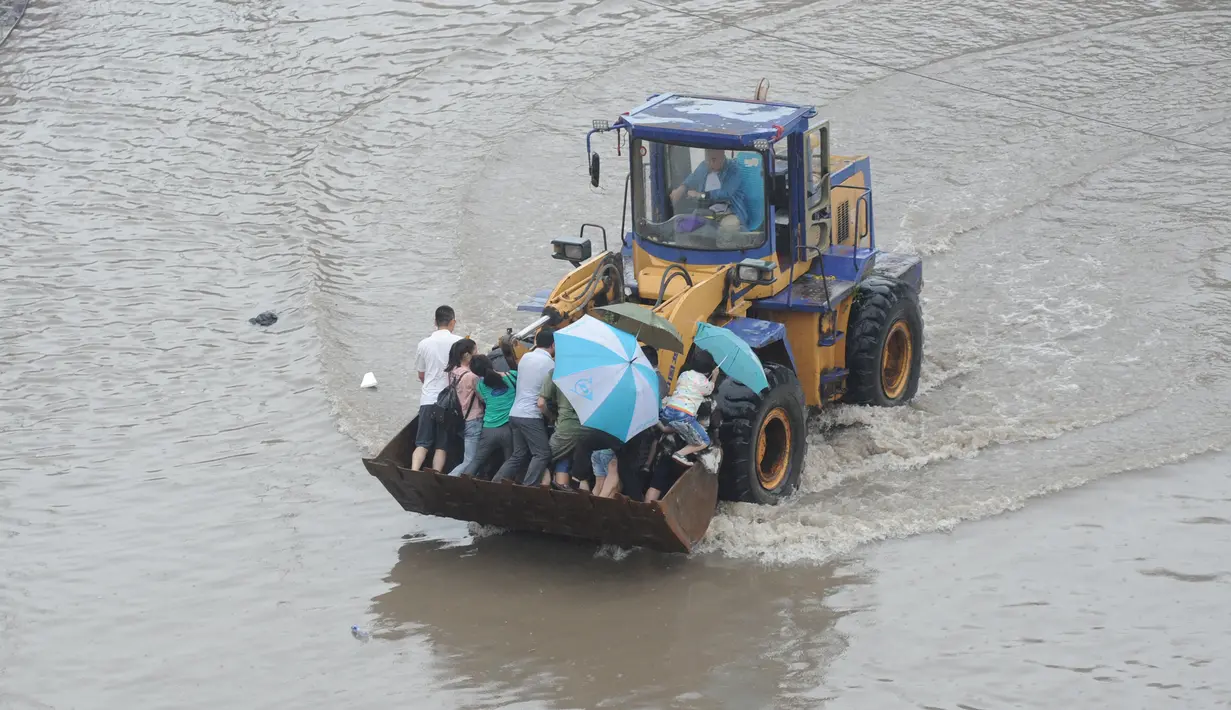 Sejumlah warga berada di ekskavator saat banjir melanda Taiyuan, Provinsi Shanxi, China, (20/7). Curah hujan terberat yang mengguyur China selama beberapa hari terakhir telah mengakibatkan banjir merendam sejumlah daerah. (REUTERS/Stringer)