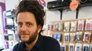 Giorgio Carbone, salah satu pendiri Mars Tapes berpose di tokonya di Manchester, Inggris, 4 September 2021. Toko yang terselip pada sudut lantai atas pasar dalam ruangan di Manchester ini menjadi toko terakhir di Inggris yang didedikasikan untuk menjual kaset. (PAUL ELLIS/AFP)