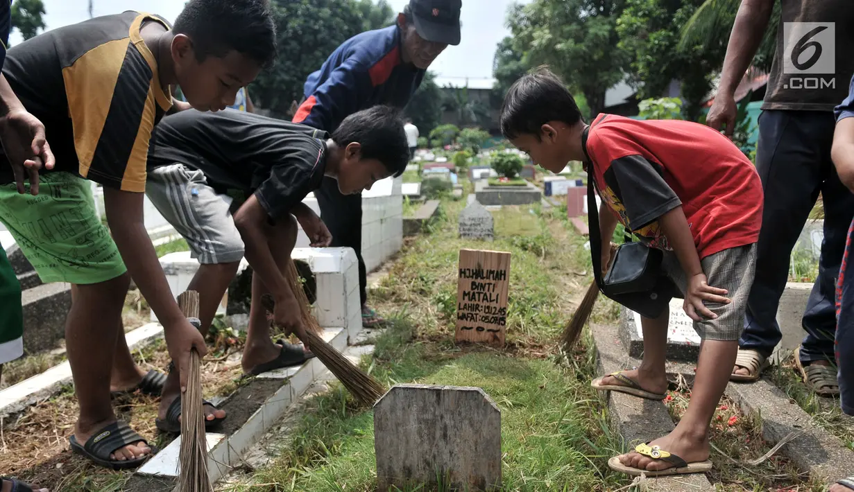 Anak-anak membersihkan makam di TPU Cipinang Baru, Jakarta, Minggu (5/5/2019). Anak-anak 'Pengoret' makam mengaku dapat mengantongi uang hingga Rp 70 ribu dari hasil ngoret yang dimulai pagi sampai sore. (merdeka.com/Iqbal S. Nugroho)