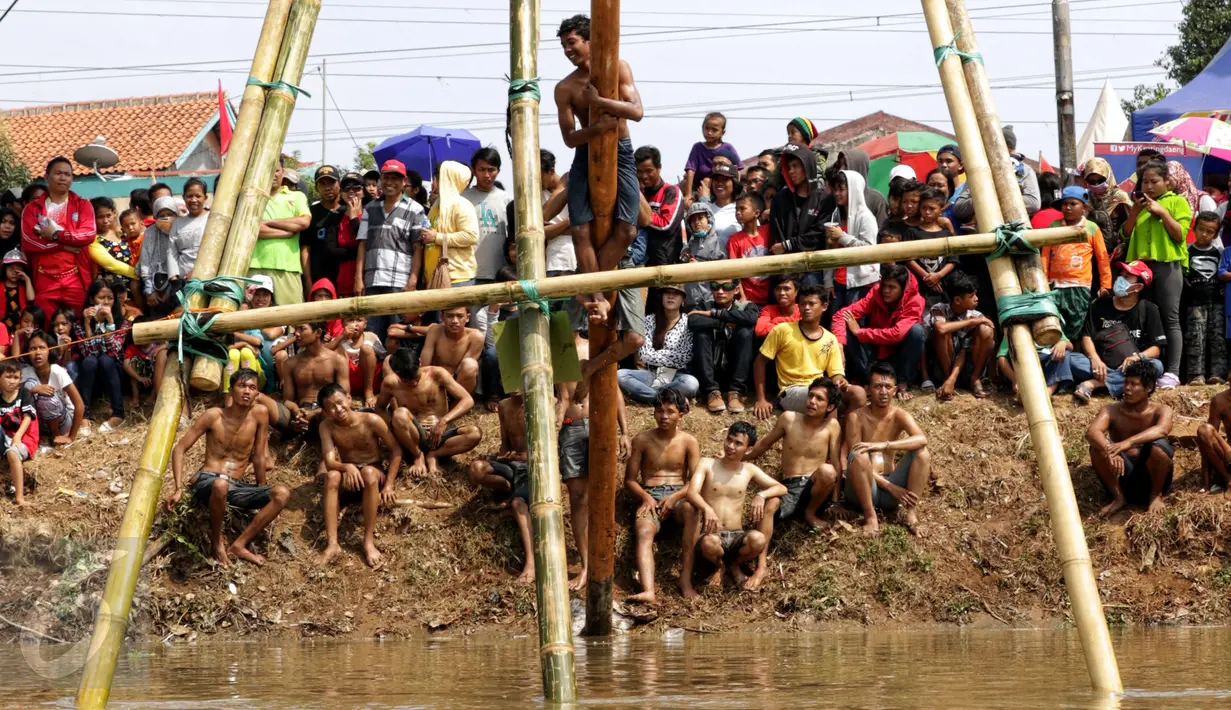 Sejumlah warga menyaksikan lomba panjat pinang dalam rangka merayakan HUT RI ke-70 di Bantaran Kalimalang, Jakarta, Senin(17/8/2015). Warga antusias mengikuti lomba panjat pinang tersebut. (Liputan6.com/Yoppy Renato)