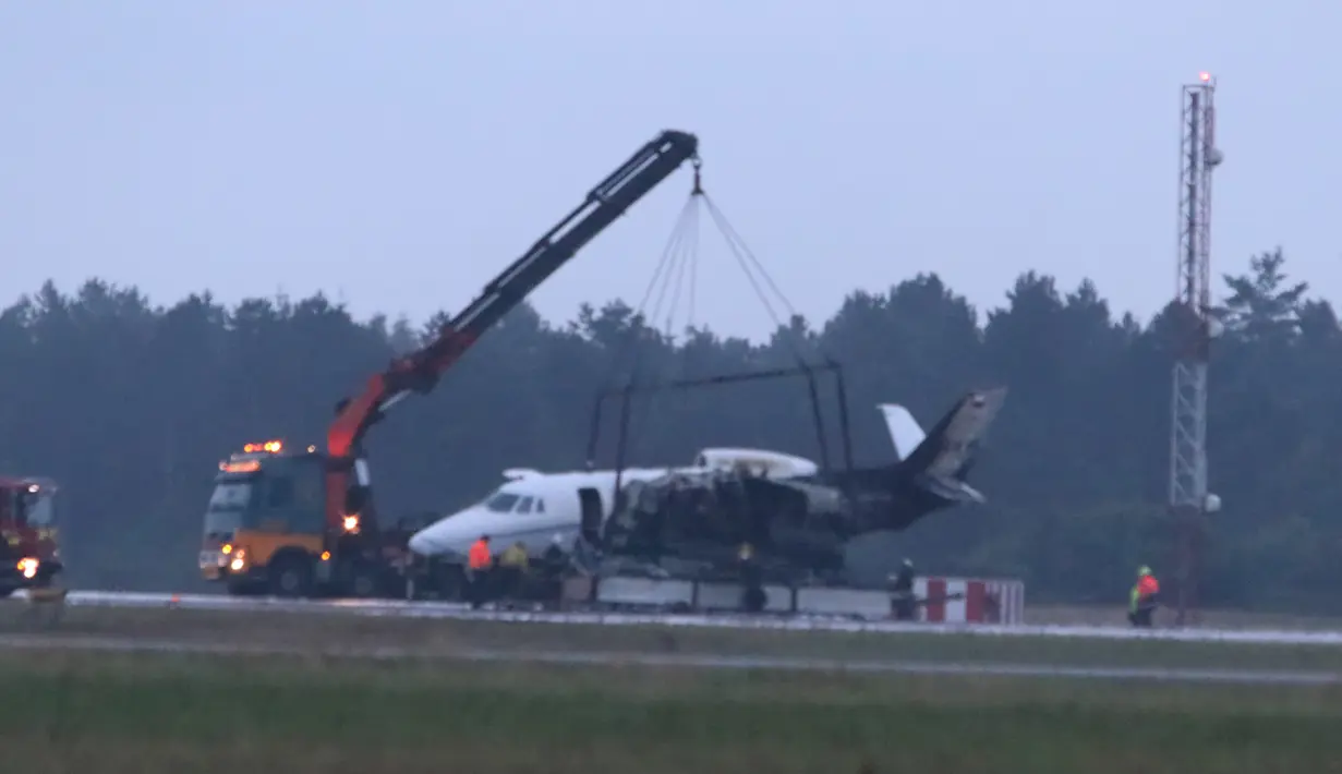 Alat berat mengangkat pesawat Cessna 560XL yang terbakar saat mendarat di Bandara Aarhus di Tirstrup (6/8/2019). Pesawat terbakar akibat roda mogok saat ingin mendarat dan pesawat mulai miring dan kebakaran terjadi di sisi kiri pesawat. (Oexenholt Foto/Ritzau Scanpix/AFP)