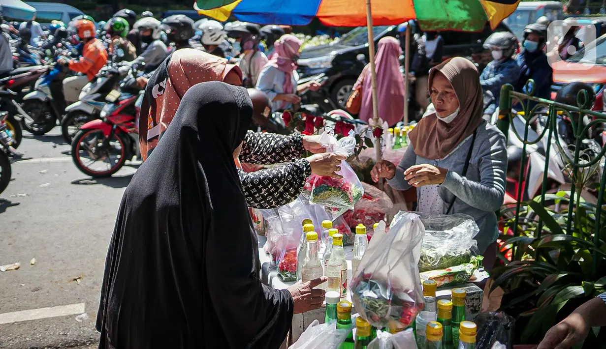 Penjual bunga tabur melayani pembeli di TPU Karet Tengsin, Jakarta, Minggu (27/3/2022). Sebagian warga memanfaatkan waktu jelang Ramadan menjadi penjual bunga tabur musiman untuk memenuhi kebutuhan ziarah ke makam yang dijual Rp 5.000 - Rp 20.000 per kantong plastik. (Liputan6.com/Faizal Fanani)
